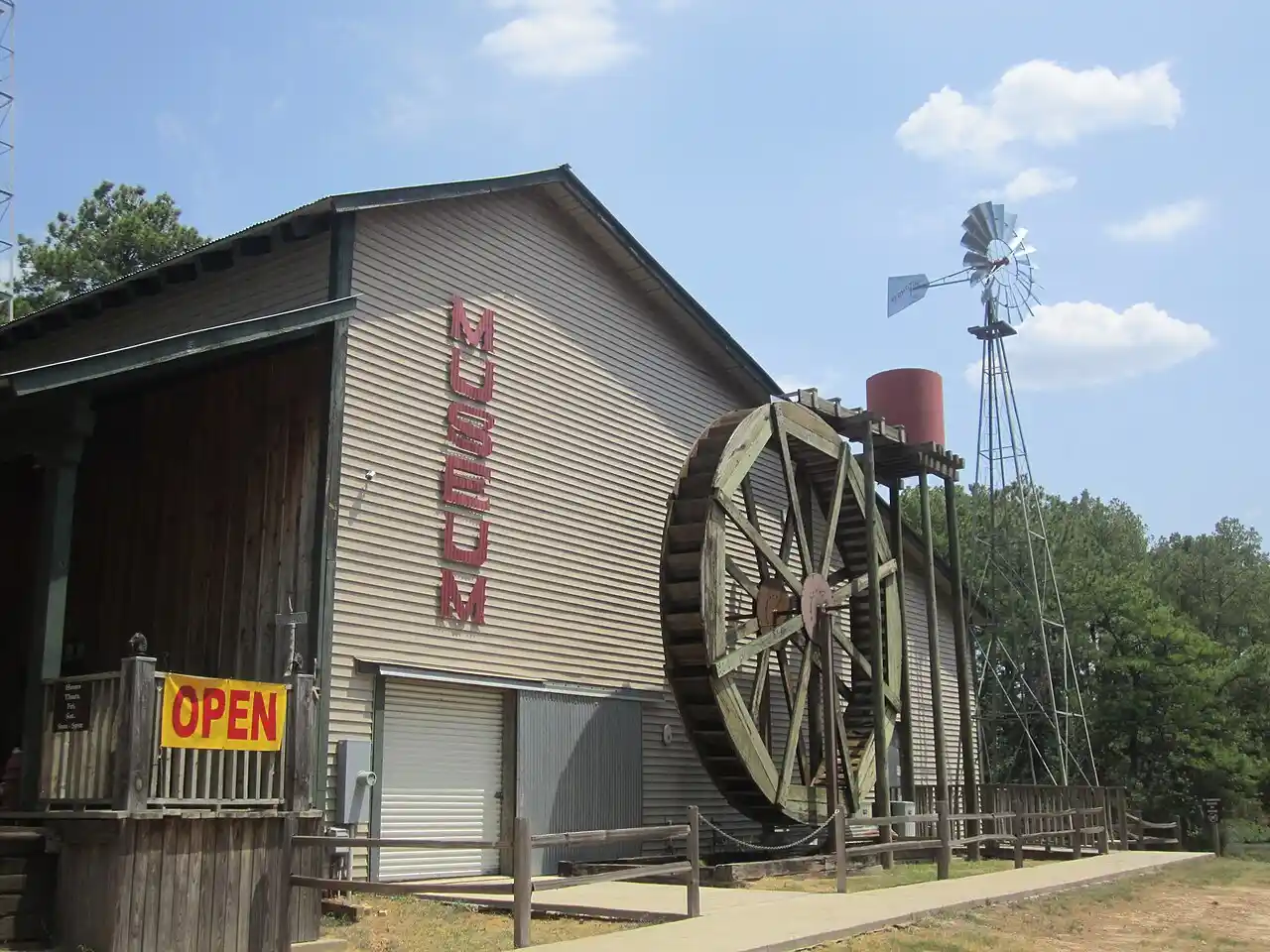 Old Mill Pond Museum Lindale Texas with operational water wheel windmill and museum building on sunny day